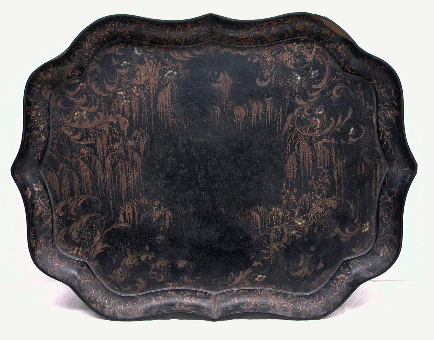 Large black lacquered tray with a deeply scalloped shaped rim, decorated with gilt scrollwork and pale inlaid shell flowers, the centre worn and finely crazed