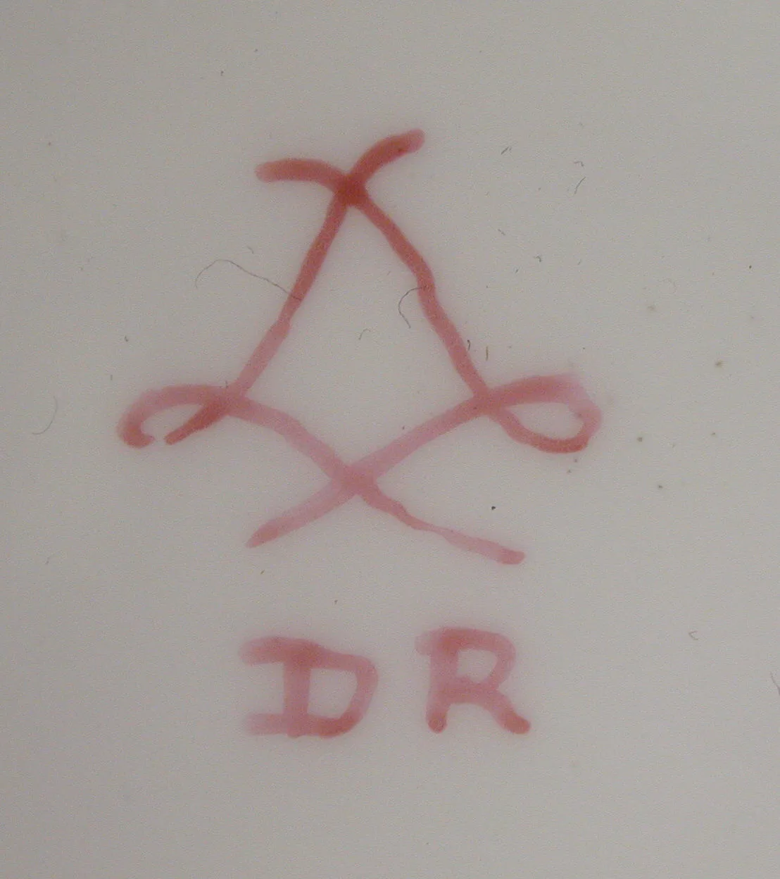 Crimson interlaced-L cipher with the initials DR below it and nothing painted inside the cipher