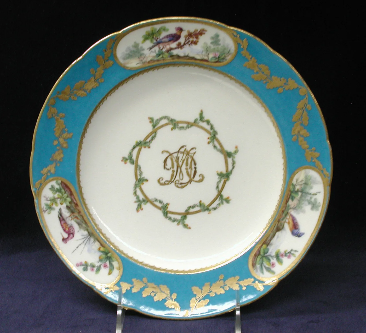Sèvres plate with a turquoise border, gilt oak-leaf swags, three oval bird reserves and a gilt monogram at the centre