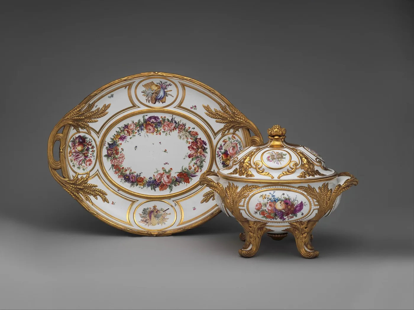 White Sèvres tureen with gilt wheat-ear handles on a matching oval stand, painted with flower garlands and small trophy medallions