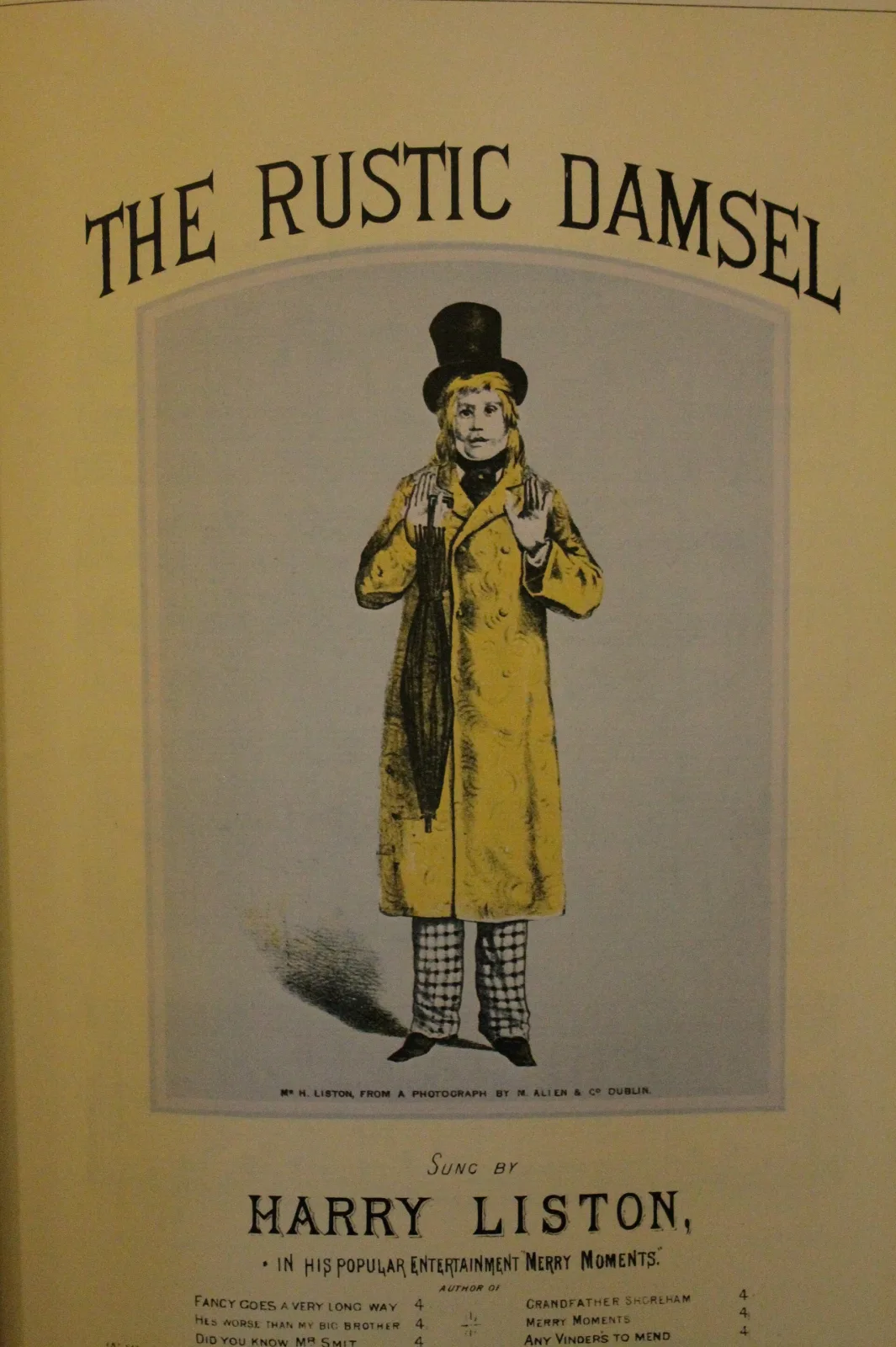 Sheet music cover with a full-length lithographed figure of a man in a long yellow coat and top hat, titled The Rustic Damsel, with the performer's name below