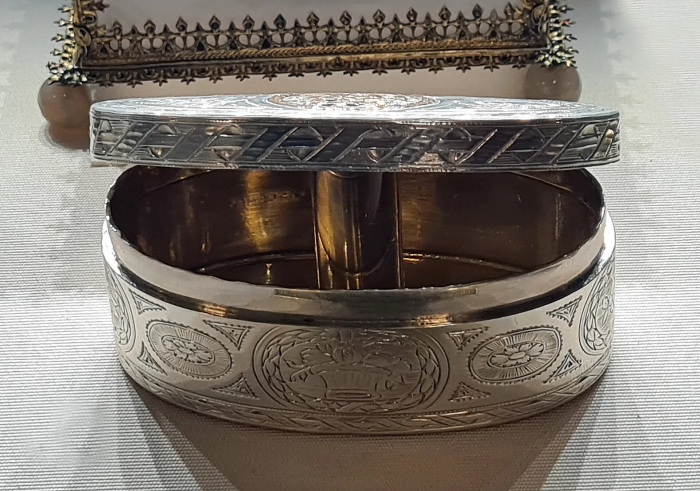 The same steel snuff box opened, showing the integral hinge and the polished interior