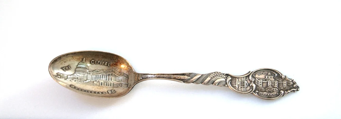 Whole silver souvenir spoon with the US Capitol embossed in the bowl and a scrolled landmark finial on a twisted stem