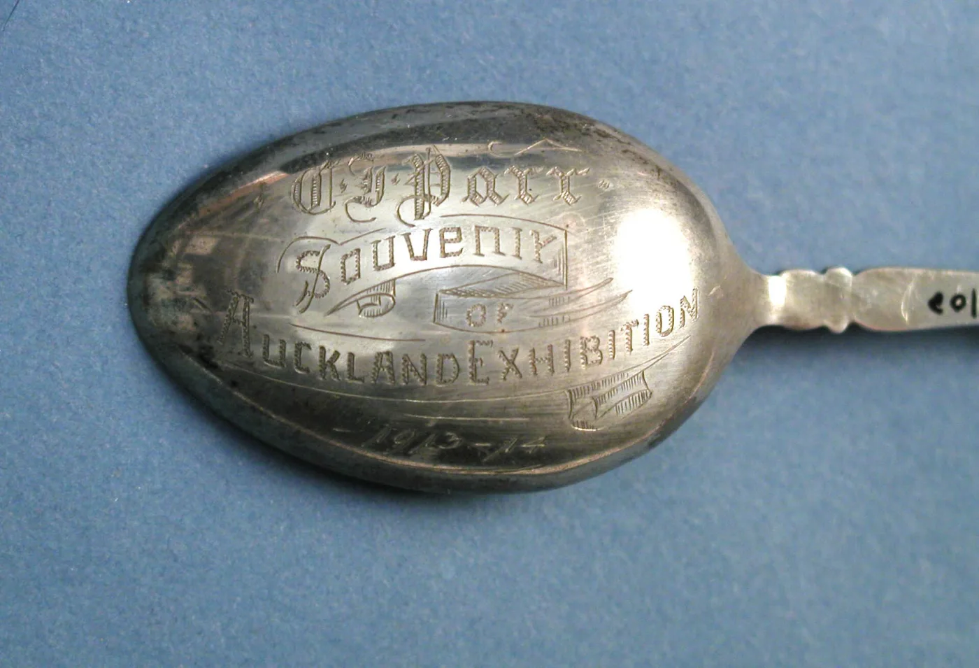 Back of a spoon bowl hand-engraved in script and block letters reading C. J. Parr, Souvenir of Auckland Exhibition, 1913-14