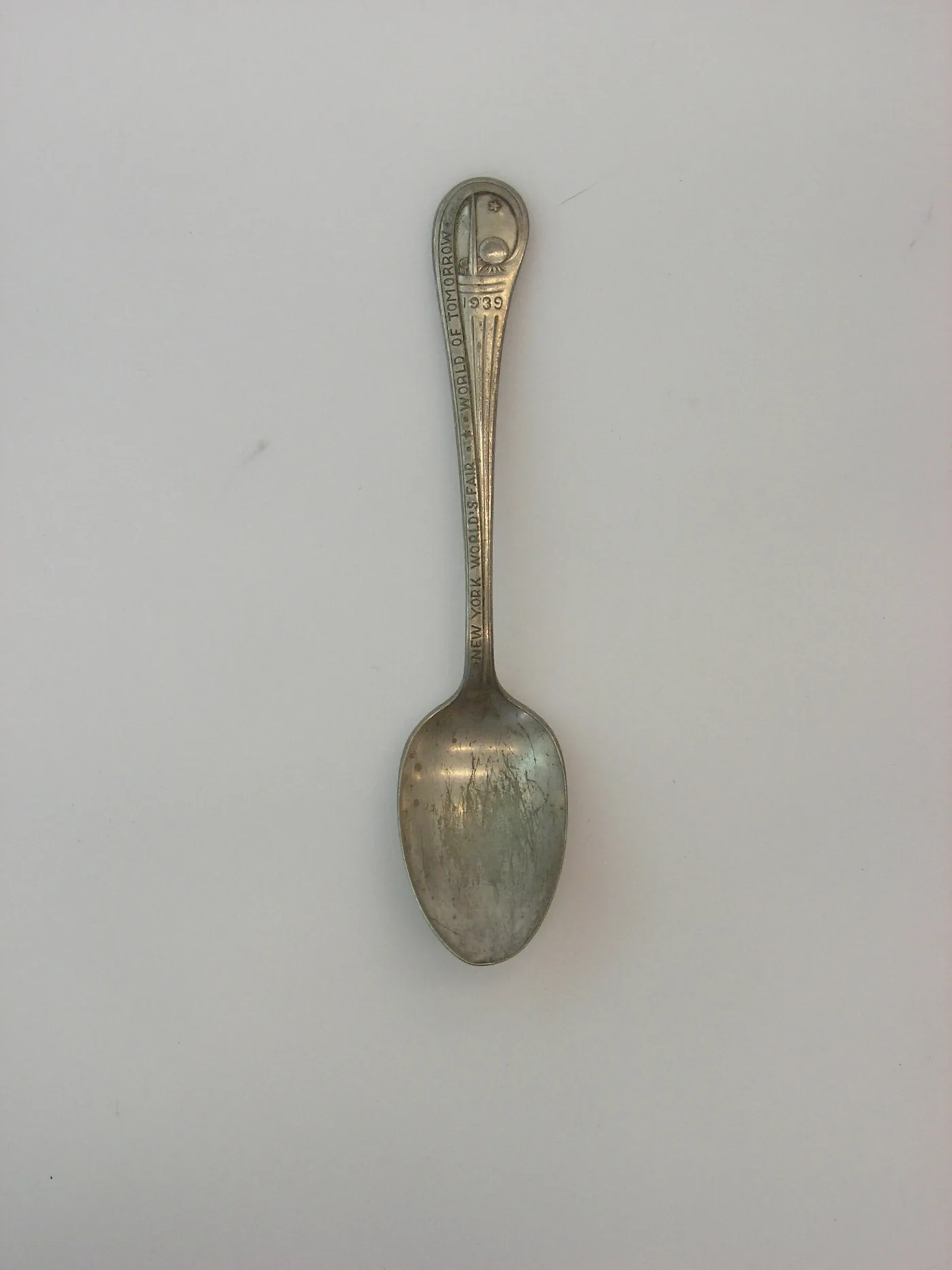 Dull grey 1939 New York World's Fair souvenir spoon whose bowl surface is mottled and breaking down