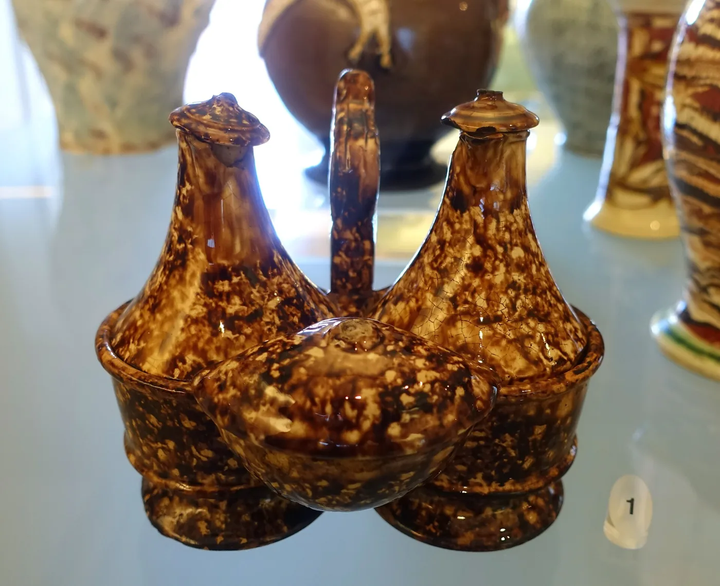 Three bottle cruet stand in mottled brown and amber, the bottles rising from a shaped base, dated about 1790 to 1860