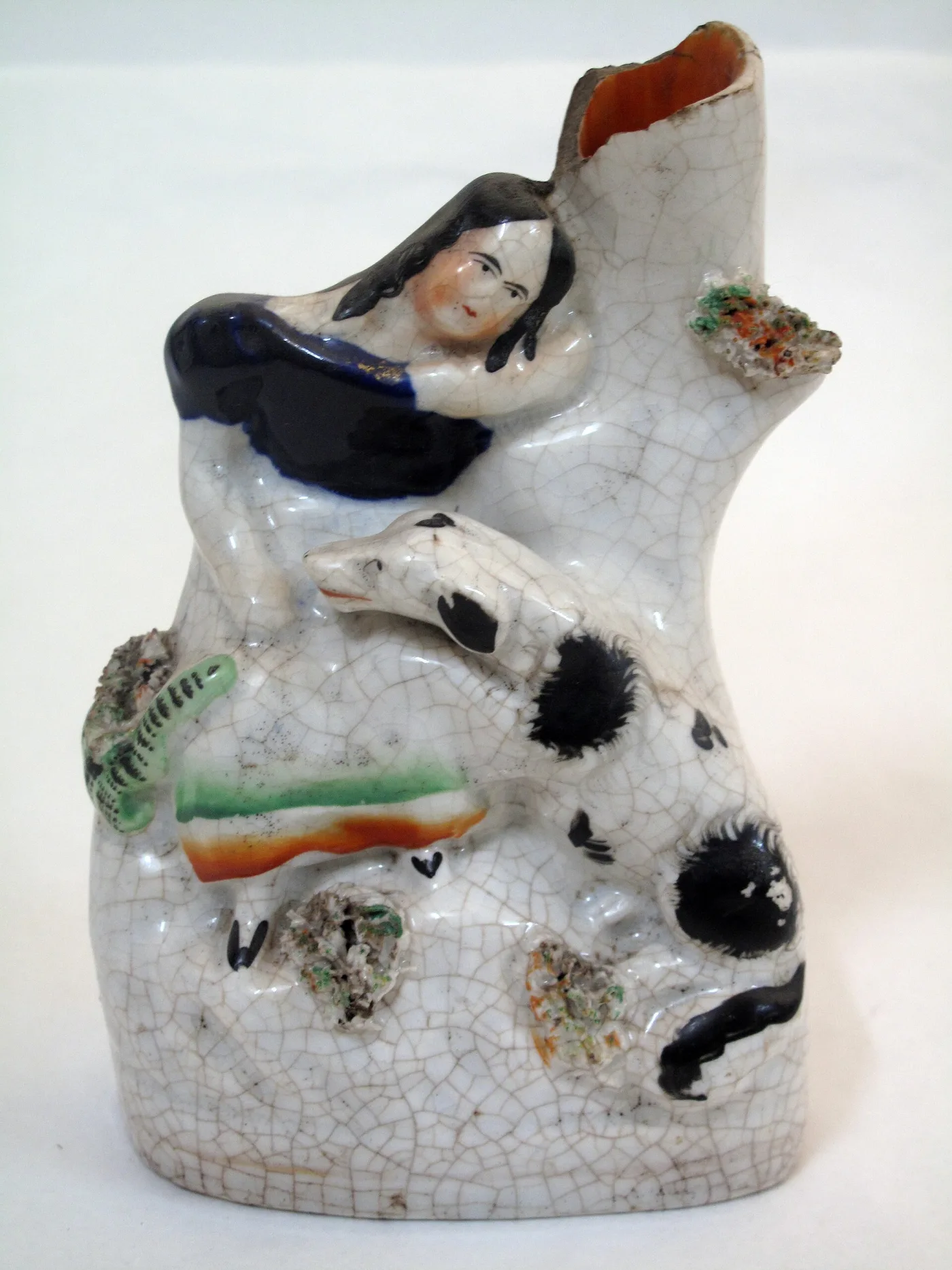 Pottery group of a dark-haired woman and a black-spotted dog against a hollow tree trunk, the whole surface covered in a fine brown-stained network of glaze cracks