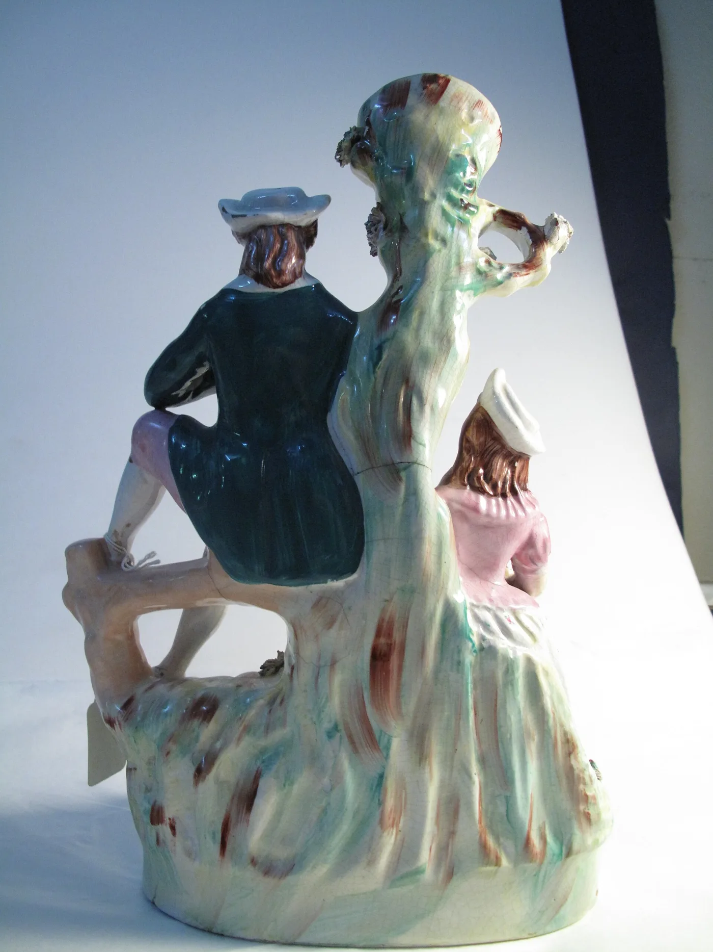 Back of the same group, fully modelled in the round, the coats and tree bark painted in loose streaks of green and brown