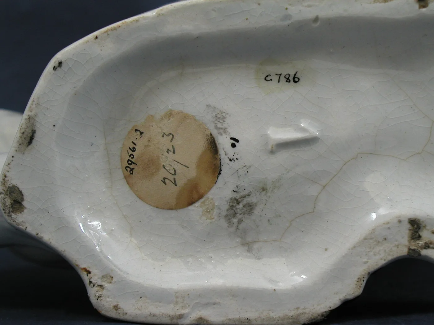 Underside of the same spaniel, showing a deep hollow interior with a glazed surface, dirt in the crevices and old ink numbers