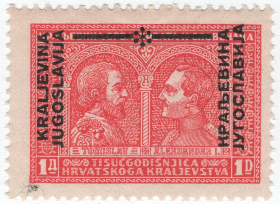 Red stamp showing two facing royal portraits, with KRALJEVINA JUGOSLAVIJA overprinted vertically in black down the left side, the same words in Cyrillic down the right, and a black bar blotting out the original country name across the top