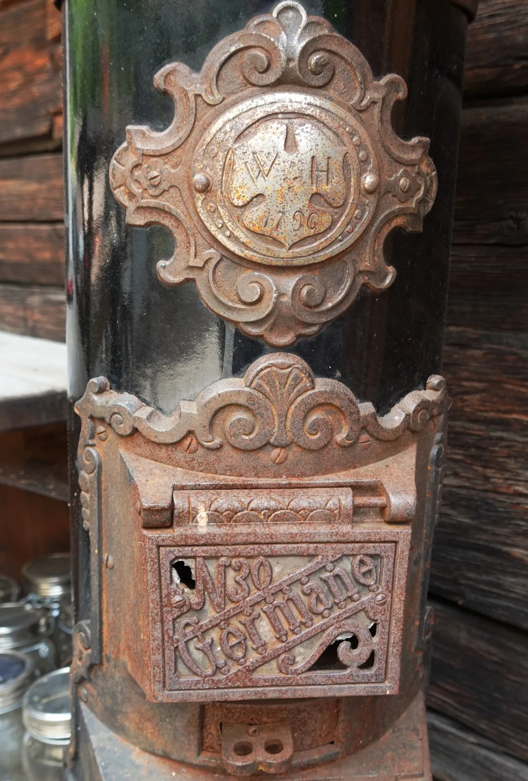 Close view of the same stove showing a shaped cast plaque with the initials W H above the date 1796, and below it a fire door with the model name Germane in raised script and the number 30