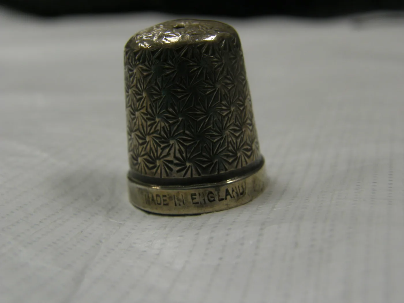The same thimble turned to bring the base band into focus, the stamped words MADE IN ENGLAND legible with further lettering continuing round out of view