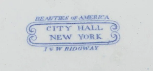 Close view of a printed blue cartouche on the white underside of a plate, reading Beauties of America above, City Hall New York inside a scrolled frame, and J and W Ridgway below
