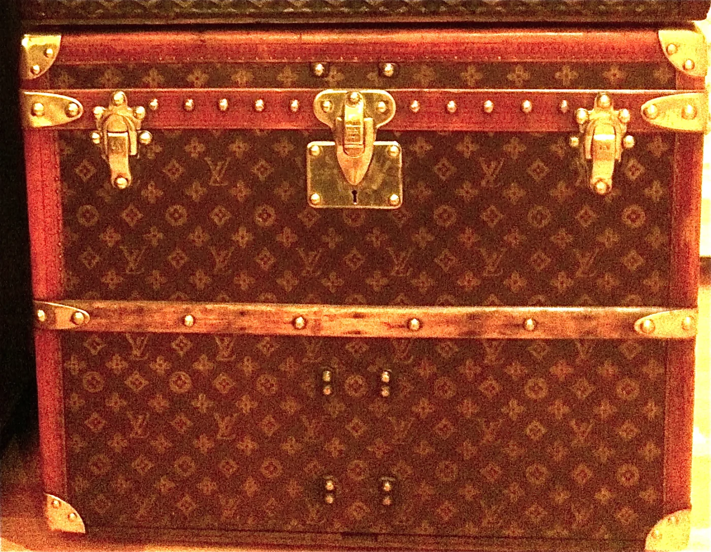 Louis Vuitton steamer trunk covered in brown monogram canvas, bound with slatted wooden ribs and leather straps, with brass corner caps, a brass lock plate and studded edges