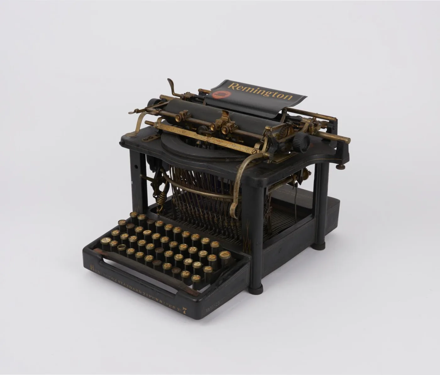 Tall black understrike typewriter with an open framework body, a wide carriage across the top, curved rows of round keys at the front and the type basket visible beneath