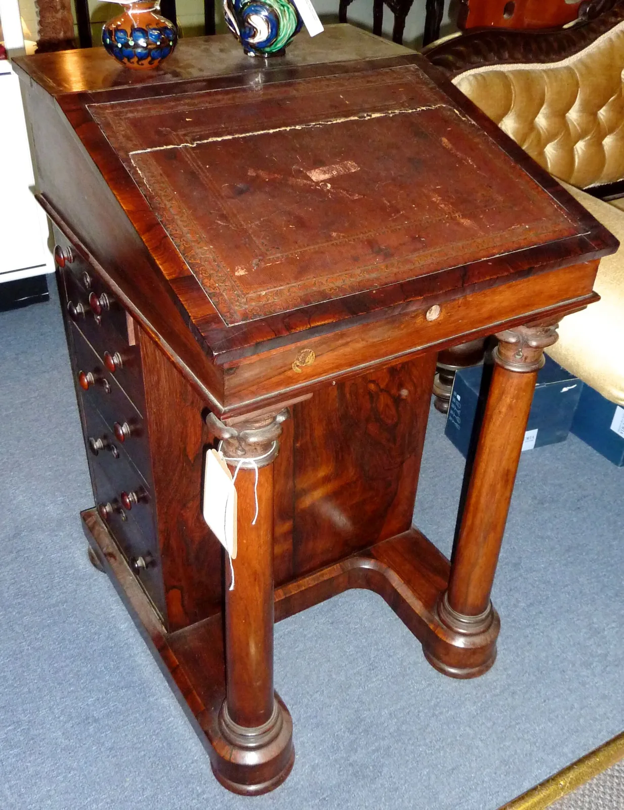 Plain rosewood writing desk with a sloped leather top over four side drawers, supported at the front by two heavy turned columns on bun feet