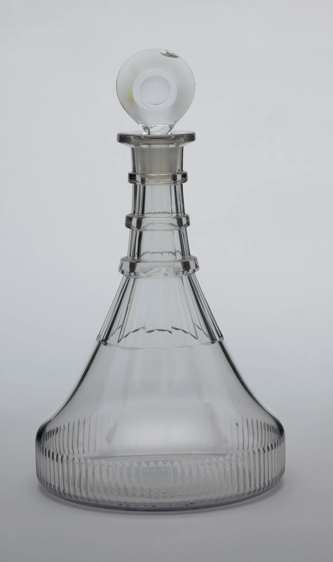 Broad-based ship's decanter of about 1810 with cut flutes round the foot, three flat neck rings and a flat disc stopper