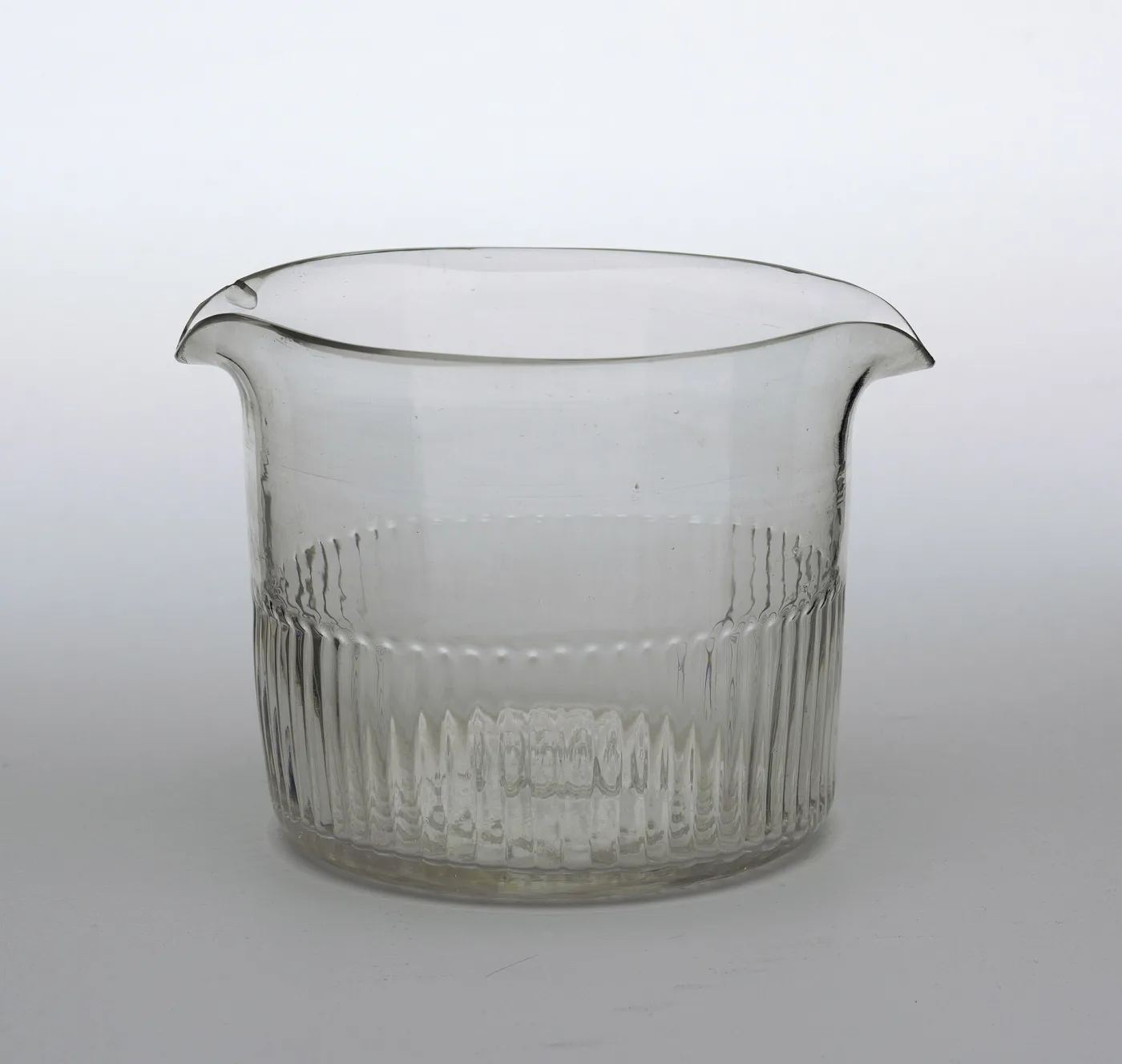 Straight-sided clear glass wine-glass rinser with two pouring lips and moulded vertical flutes around the lower body