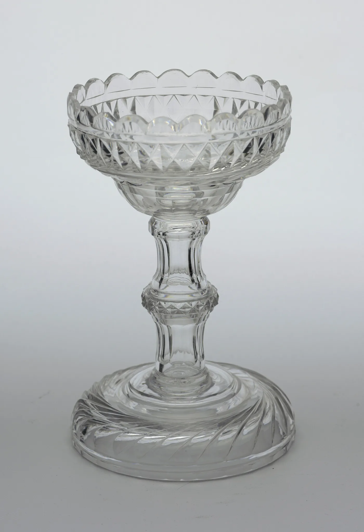 Tall footed sweetmeat glass of about 1810 with a scalloped rim, a band of cut diamonds and a swirl-cut domed foot