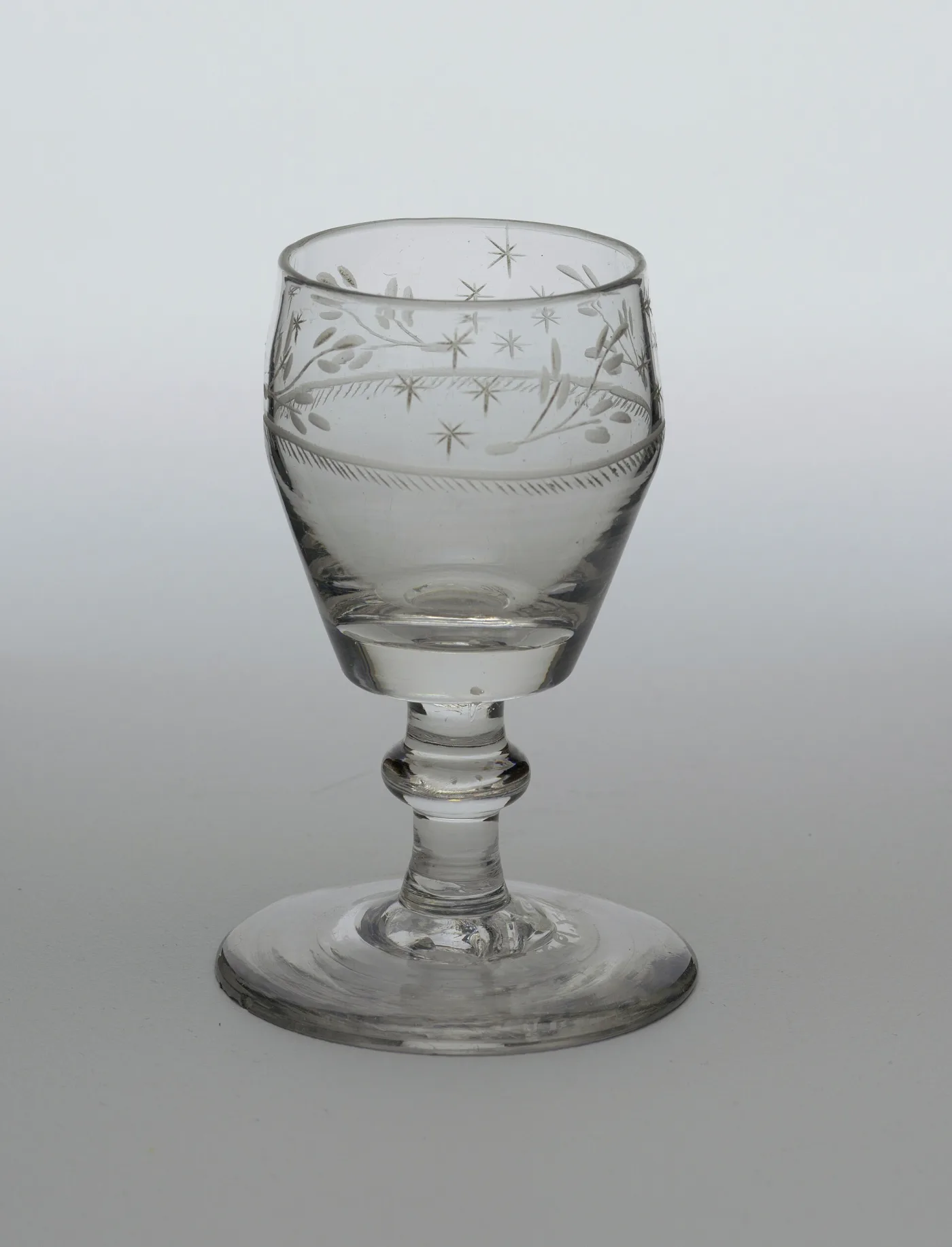 Small footed goblet of about 1810 to 1825 engraved round the bowl with leafy sprays and six-pointed stars above a hatched band
