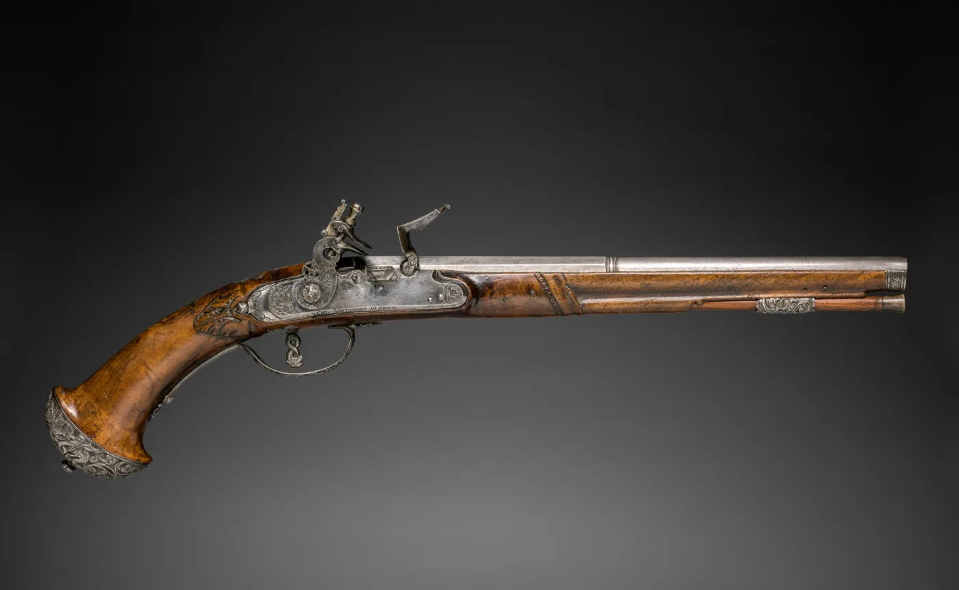 The companion pistol of the same pair, closely matching in barrel length, lock shape, stock carving and mounts, photographed against the same black ground
