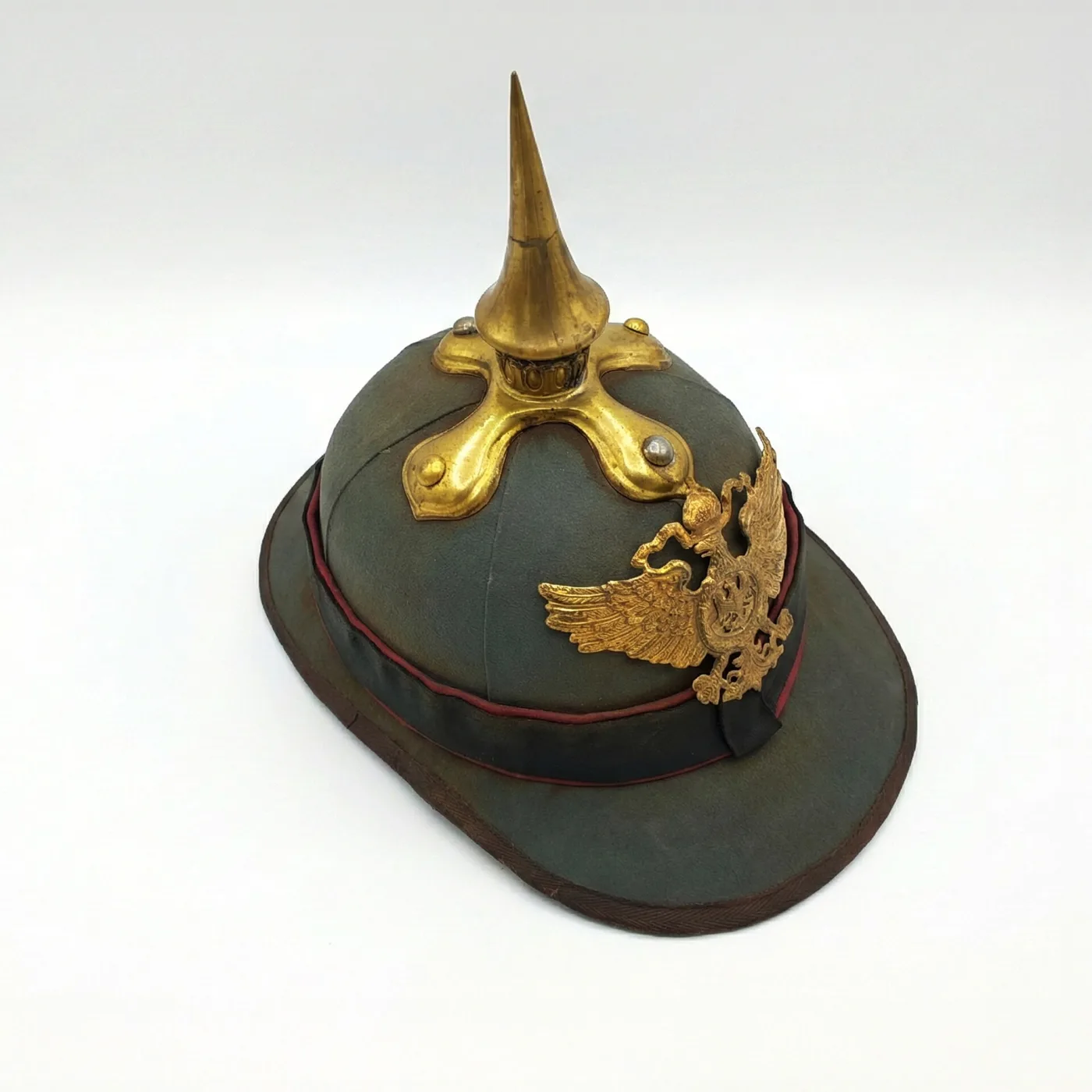 Khaki tropical sun helmet fitted with a gilt spike and a large gilt sunburst plate bearing an imperial eagle, displayed against a plain dark ground