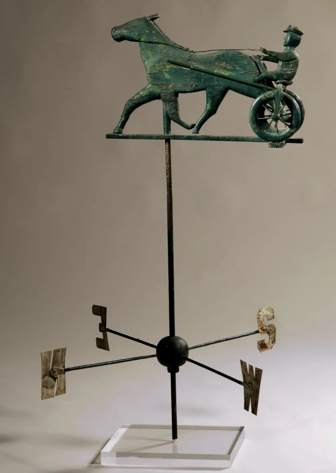 A carved and painted wooden weathervane of a horse pulling a sulky with a driver, the sulky fitted with small rubber tires