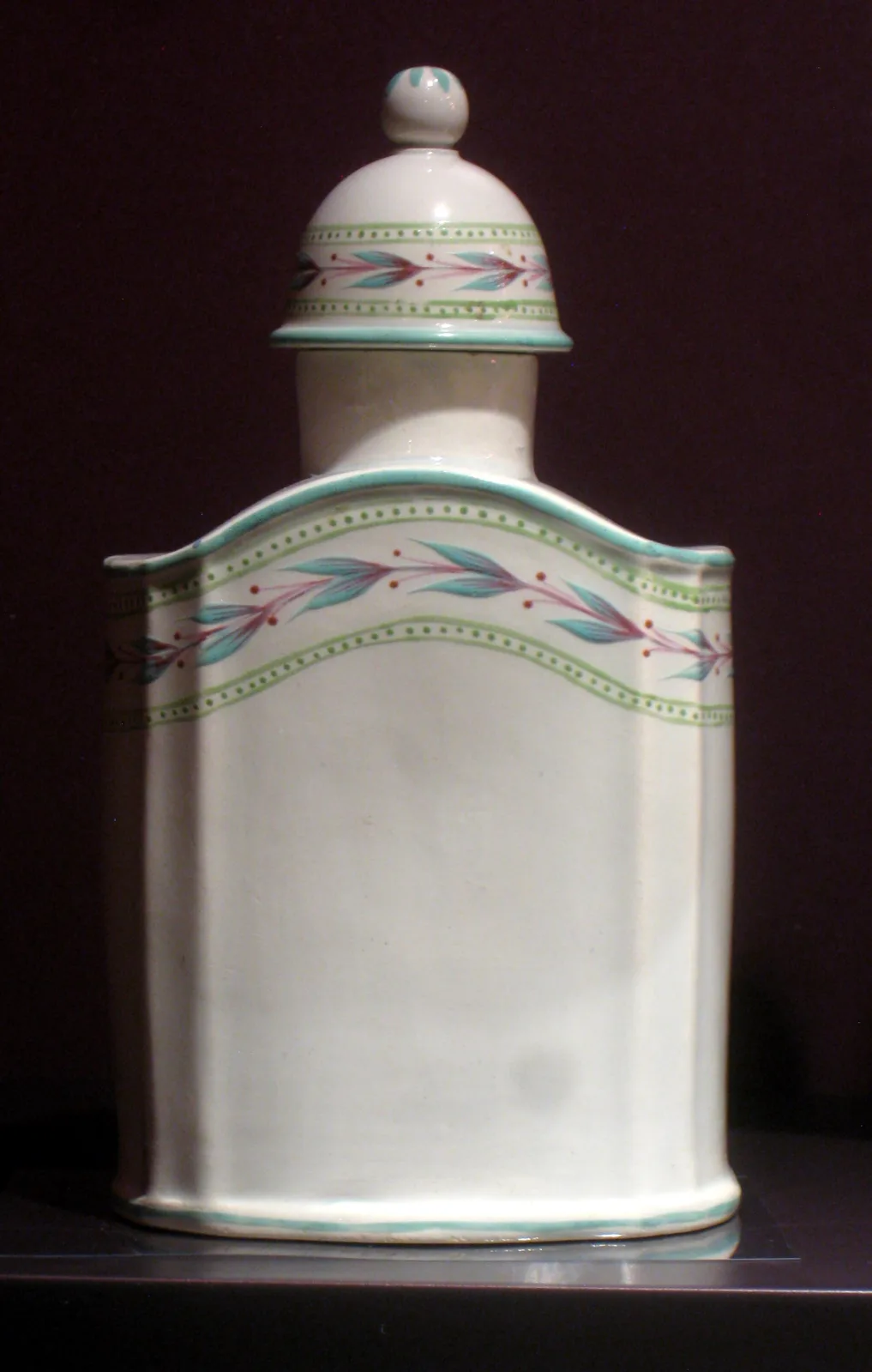 Upright rectangular tea canister with rounded shoulders and a domed lid, in pale bluish-white pearlware painted round the shoulder with a band of pink and green flowers
