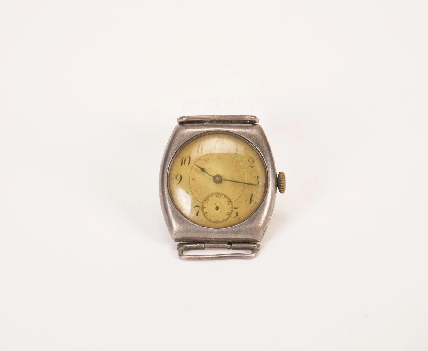 Silver cushion-shaped wristwatch case with hinged bar lugs, a gilt dial with black Arabic numerals and a red inner 24-hour ring