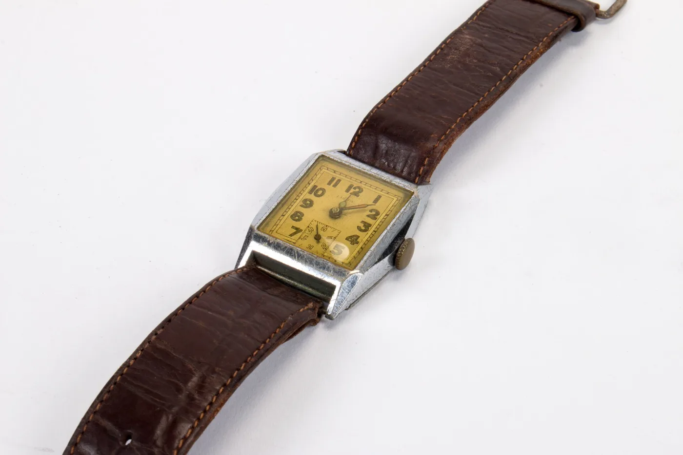 Rectangular Art Deco wristwatch with a stepped chrome case, champagne dial with Arabic numerals and a brown leather strap