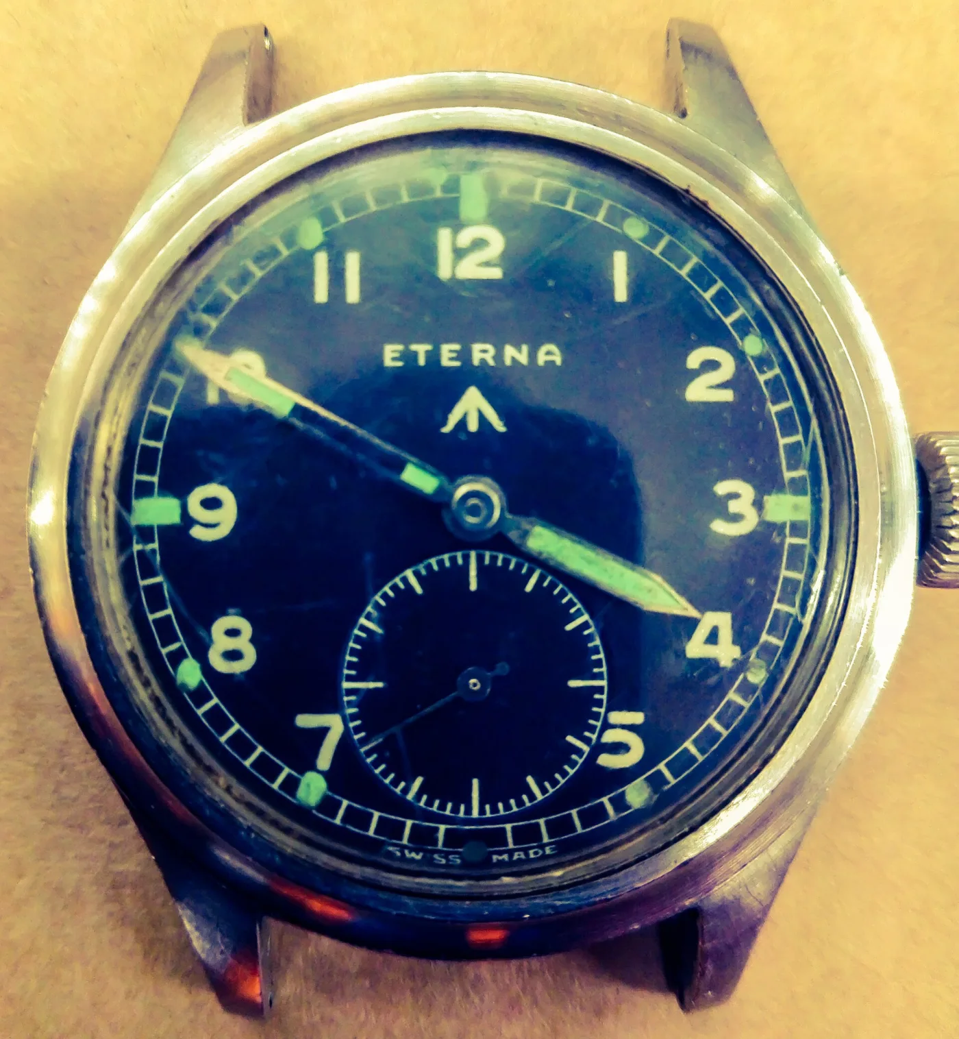 Black military wristwatch dial signed Eterna with pale green luminous Arabic numerals, a broad arrow mark and subsidiary seconds