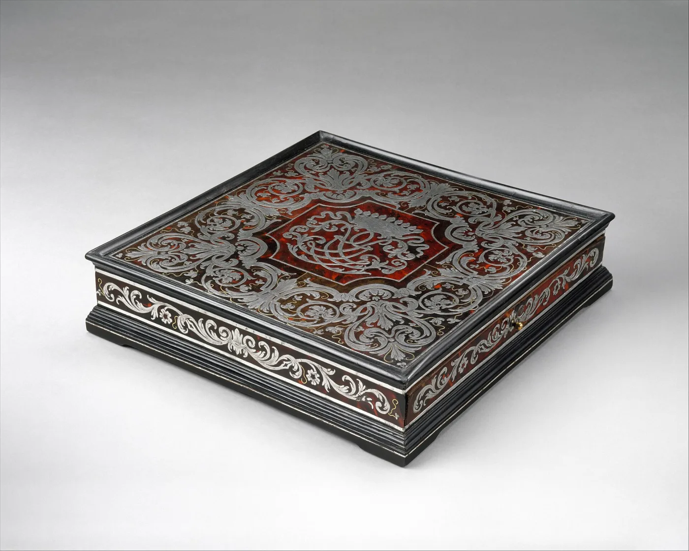 The same writing box seen from a low angle, showing the moulded base, the depth of the sloped lid and the pattern continuing over the front edge