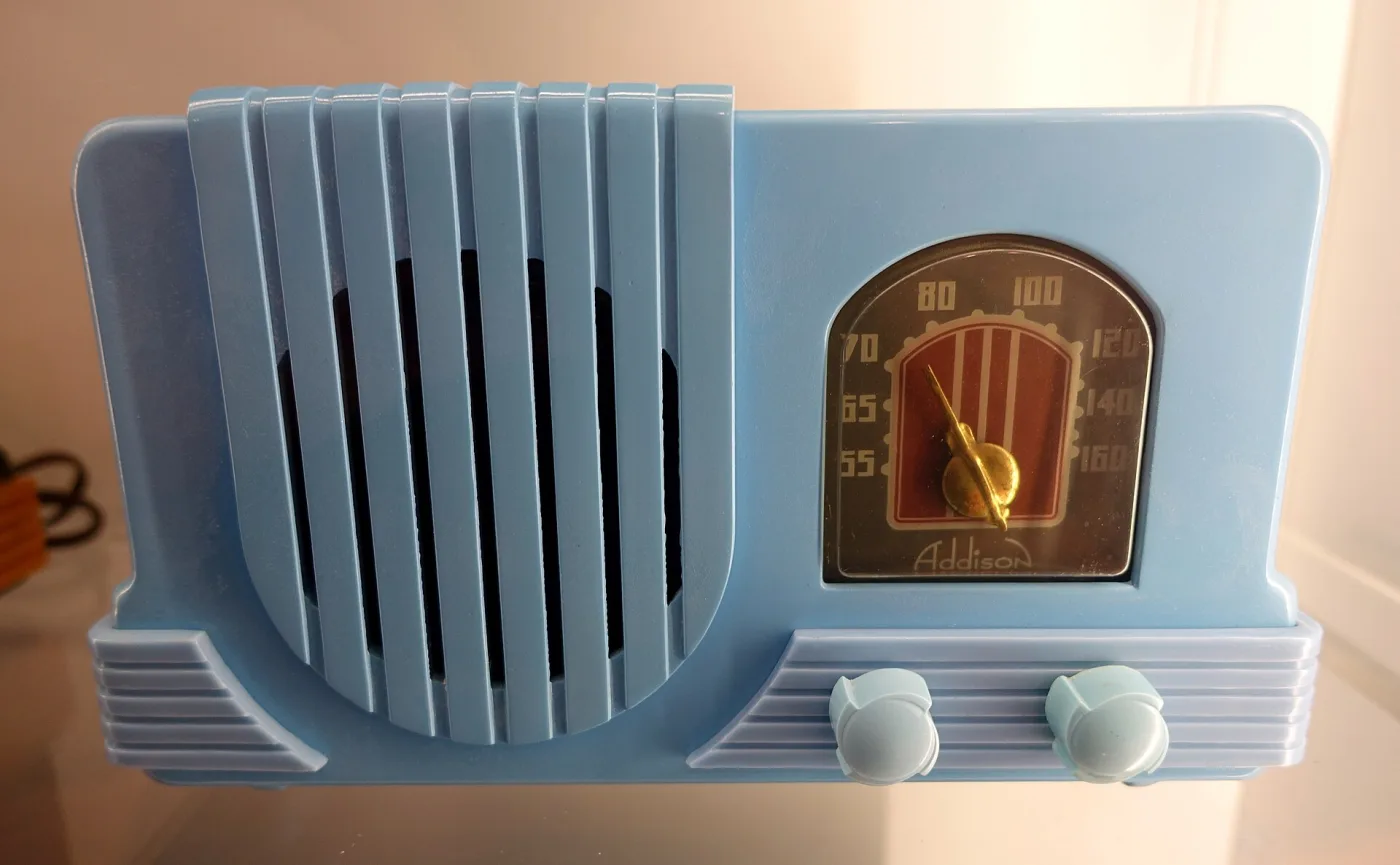 Table radio of 1940 in a pale blue cast plastic case with vertical fluted grille bars, a stepped body, an arched dial window and two round knobs below