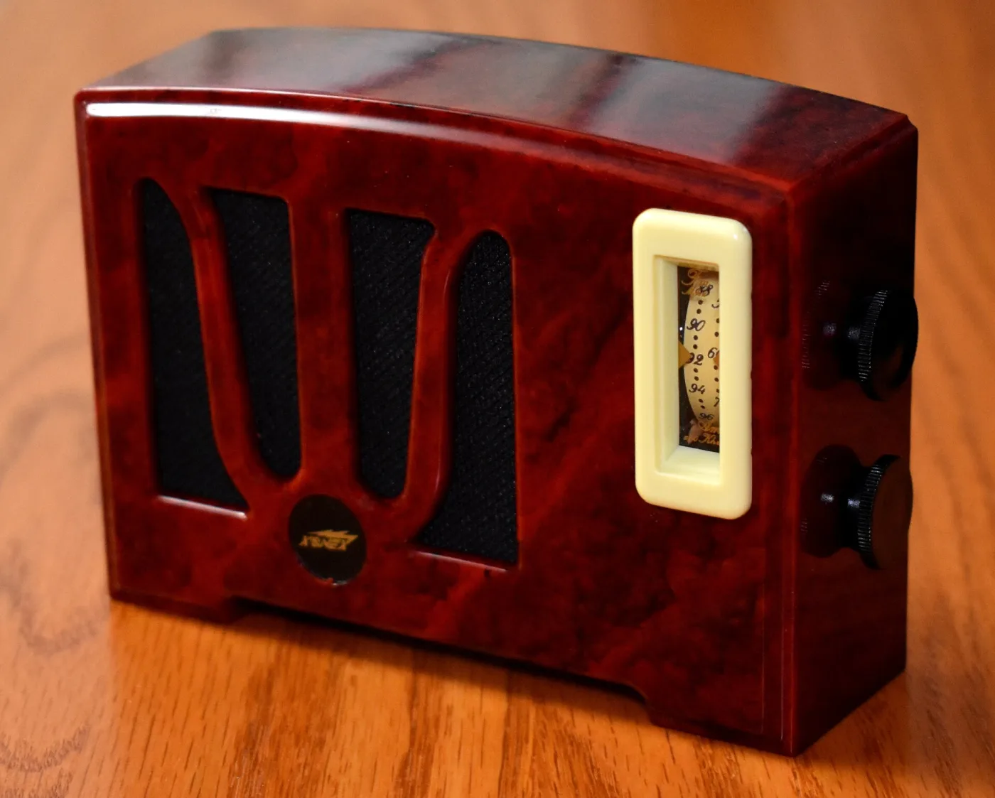 Table radio in glossy red-brown swirled plastic with a wide horizontal grille of pale bars and two round knobs, closely resembling a 1940s cast plastic cabinet