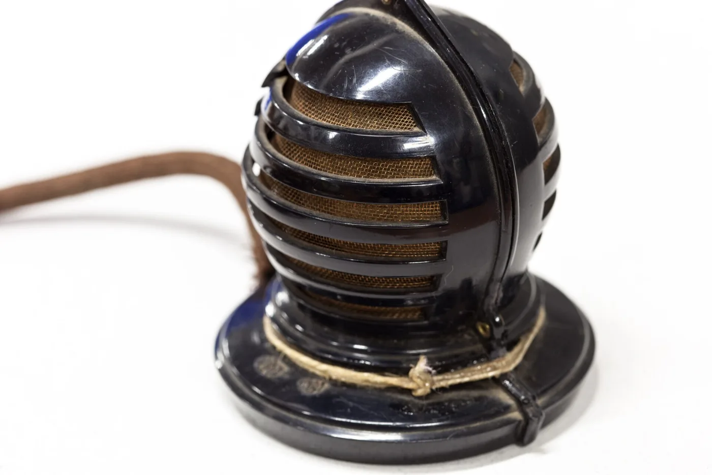 Black moulded desk microphone of about 1930, shaped as a ribbed dome on a heavy circular base, with a fabric-covered lead running from the back