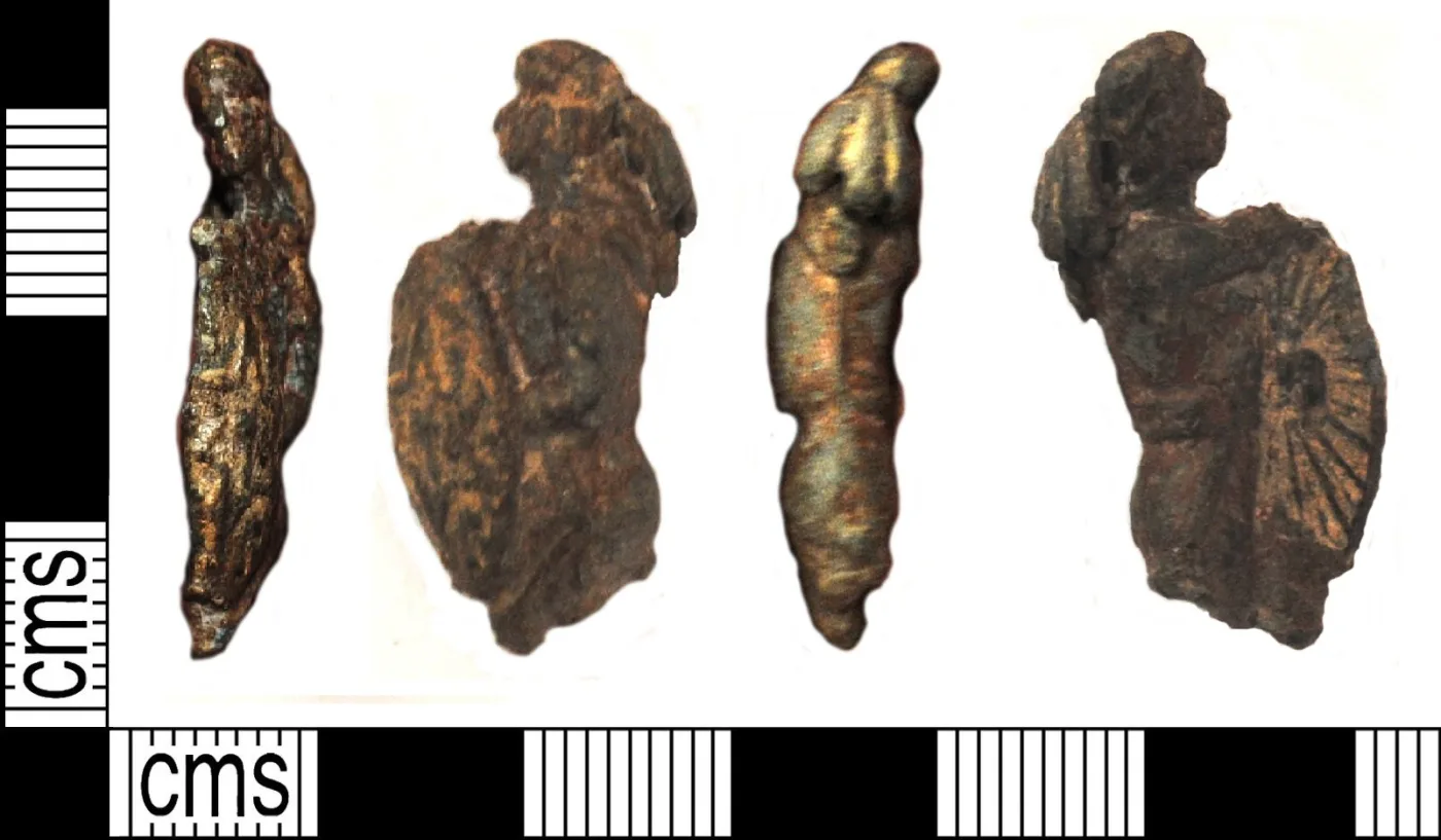 Four views of a small, heavily corroded cast figurine of a warrior, the surface pitted and dull grey with patches of surviving cold paint, photographed beside a centimetre scale