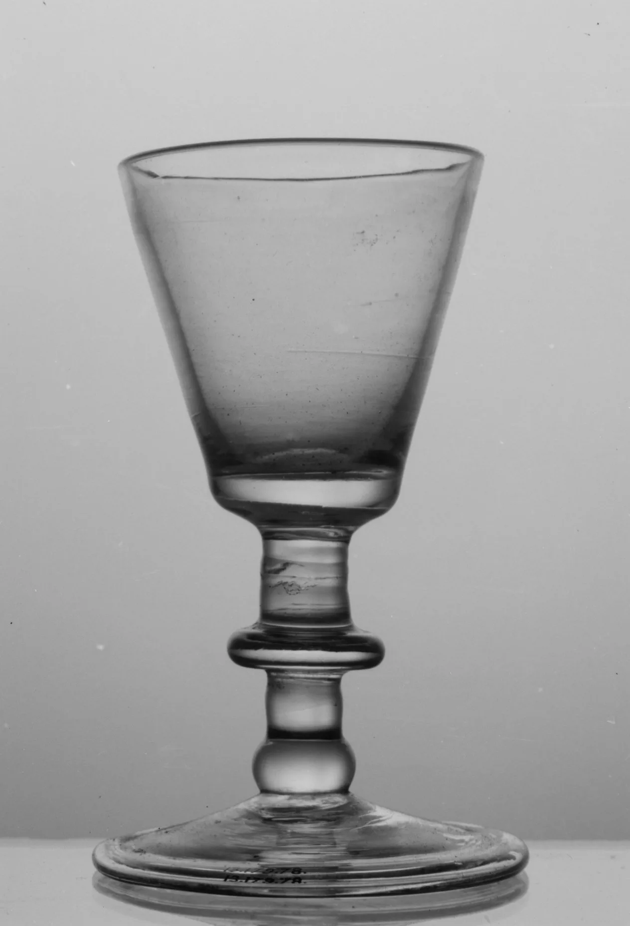 English baluster wine glass with a plain conical bowl, an annulated flattened knop above a ball knop, and a folded conical foot