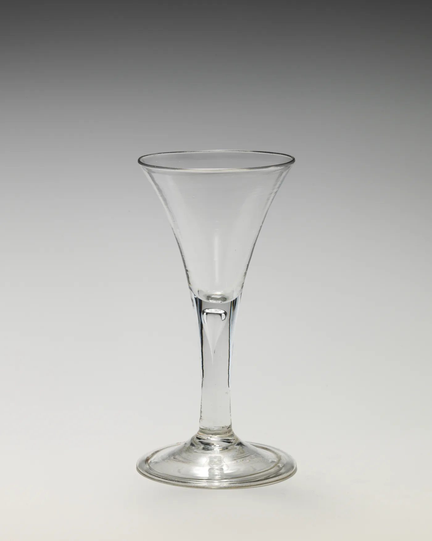 English drawn trumpet wine glass with a plain stem containing one elongated tear and a plain conical foot