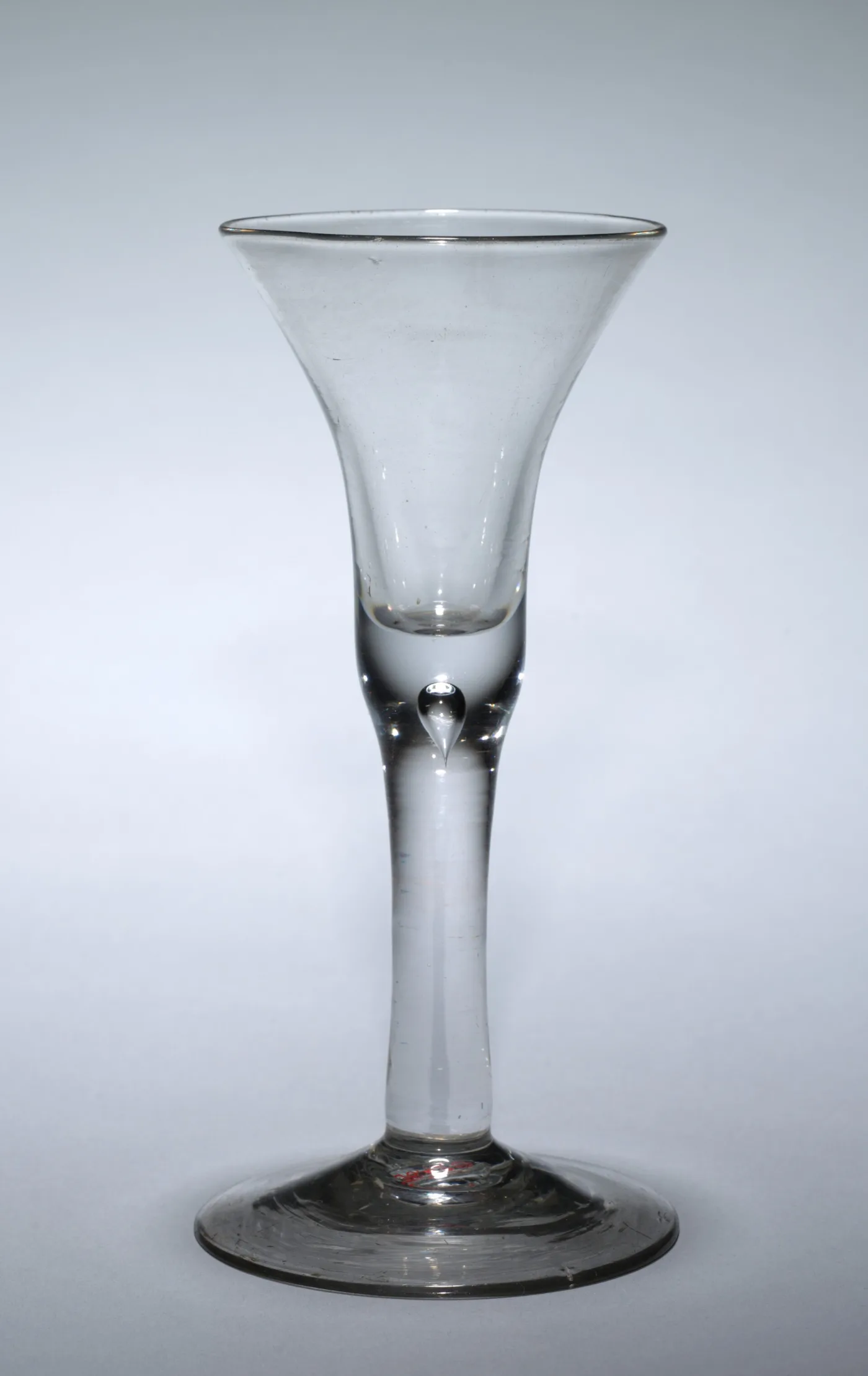 English wine glass dated about 1700 to 1725 with a drawn trumpet bowl and a plain tapering stem holding a single tear