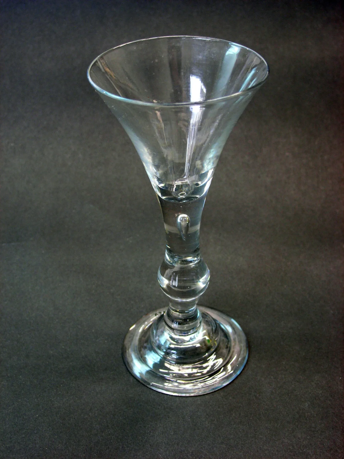 English balustroid wine glass with a trumpet bowl, an elongated tear in the stem above a basal knop, and a domed foot