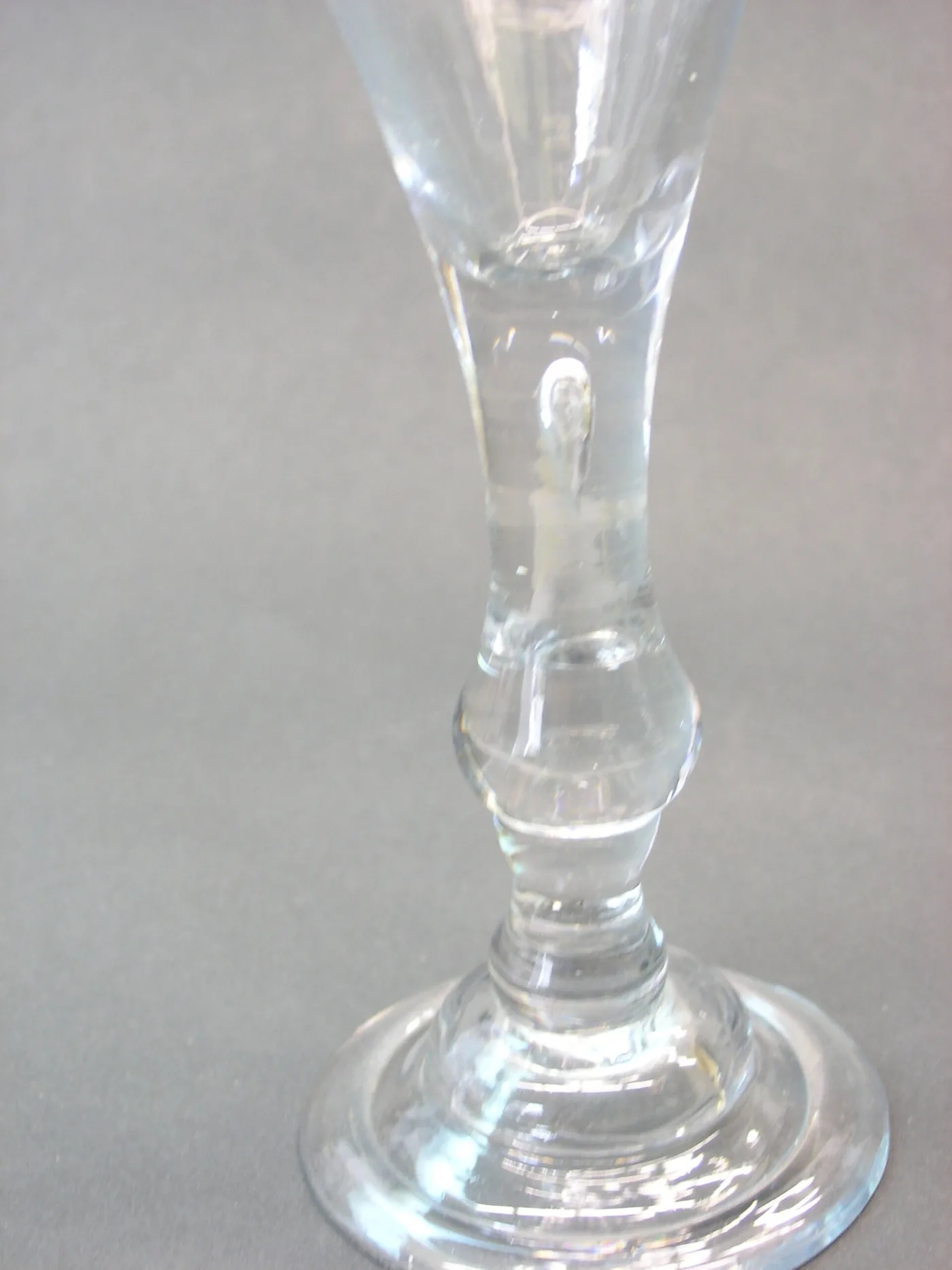 Close view of the same baluster stem showing the elongated tear, the basal knop and the domed foot