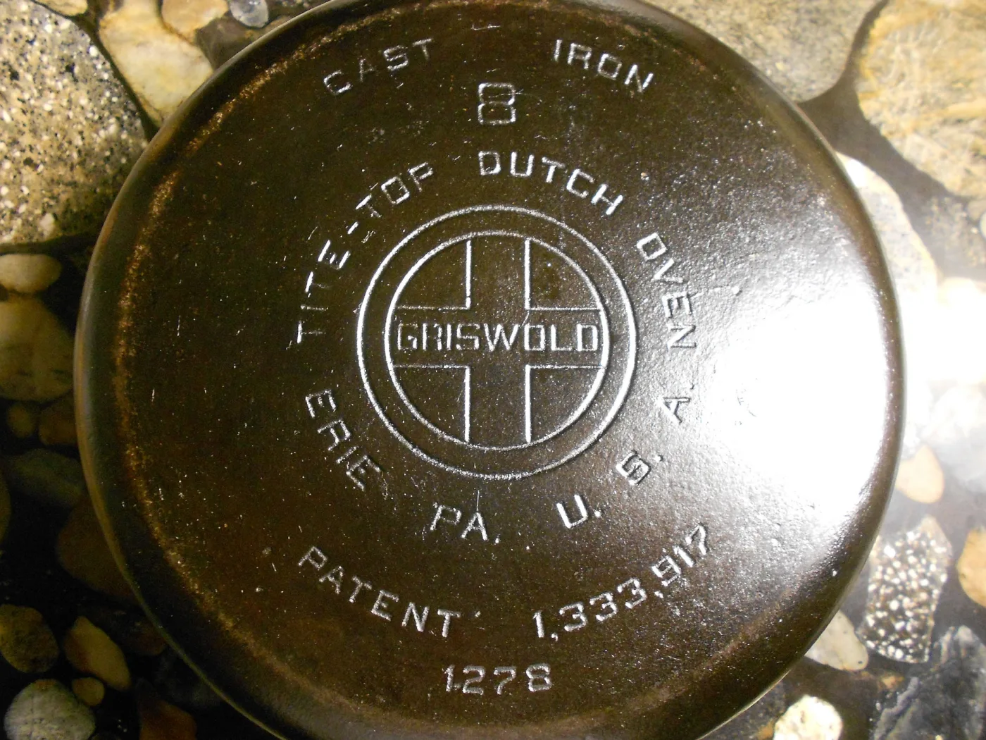 Base of a Griswold Dutch oven showing the cross logo with GRISWOLD in upright block letters, the words Tite-Top Dutch Oven, Erie PA. U.S.A., a patent number and the size number 8