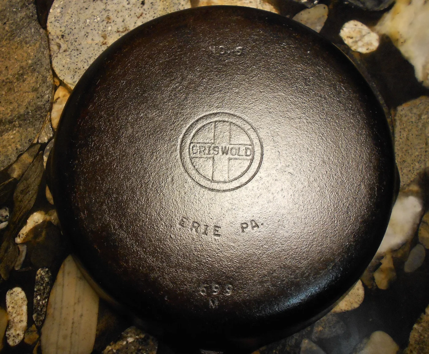 Base of a Griswold skillet with a small cross logo in the centre, the name Griswold in block letters and ERIE PA below it