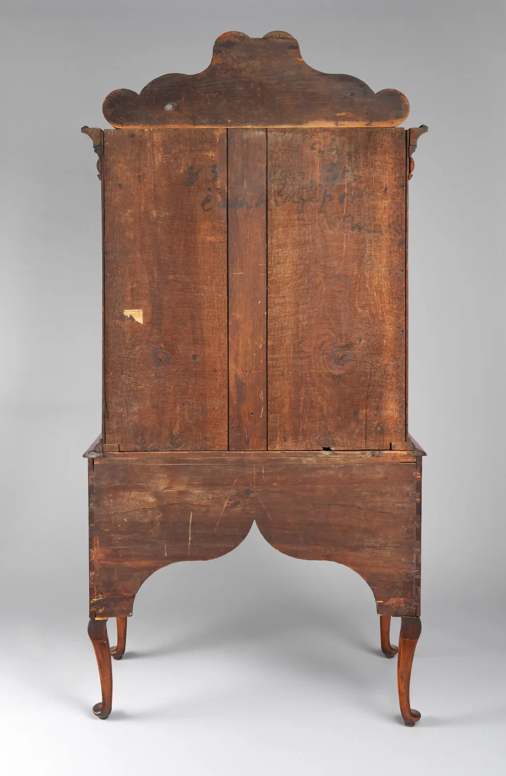 The back of a walnut high chest of drawers, with vertical unfinished boards on both the upper case and the lower case, all of a similar brown colour