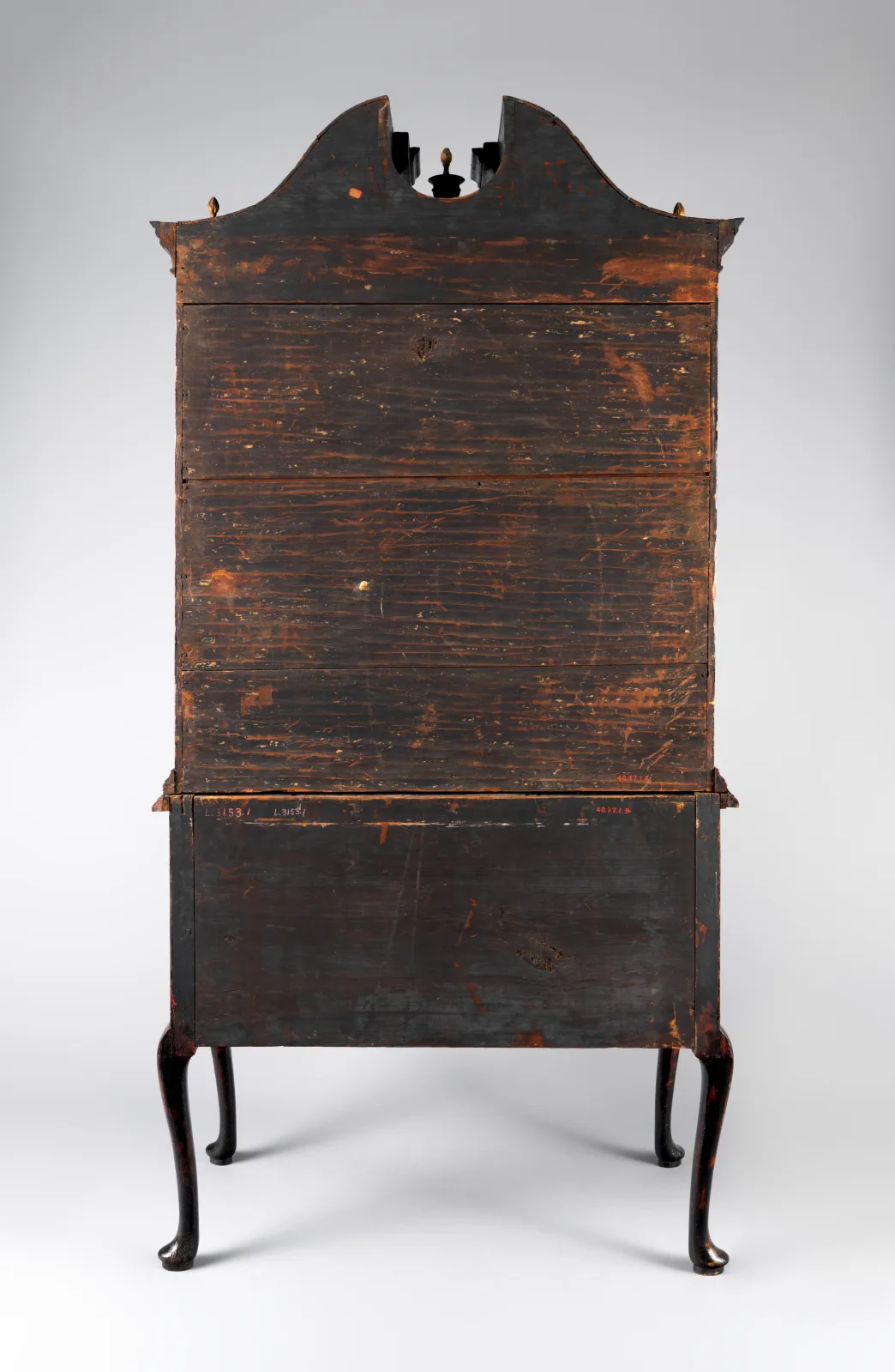 The back of a japanned high chest of drawers with rough horizontal boards across the upper case and a darker lower case on slender cabriole legs