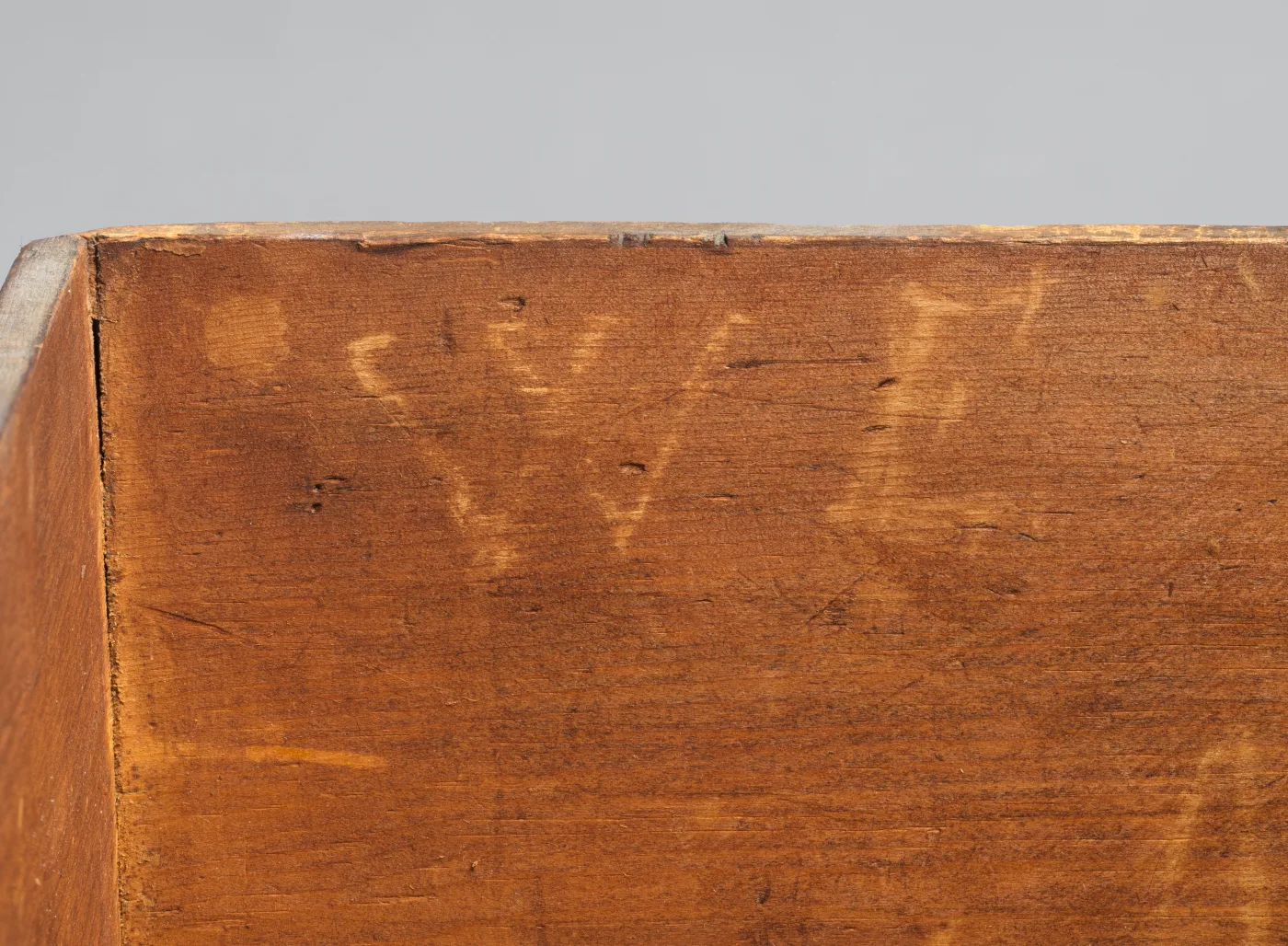 Close view of the unfinished end of a pine board with large pale chalk letters written across its face