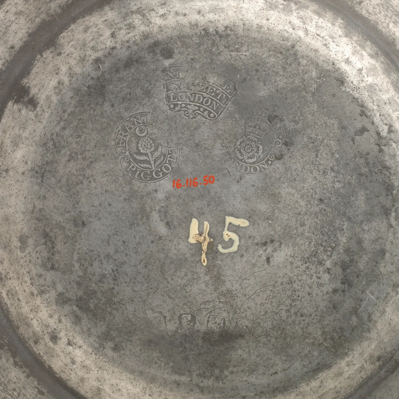 Back of a grey pewter plate with three struck marks: a round touch with a flower and the name FRAN PIGGOTT, a crowned oblong mark ending LONDON, and a crowned rose with LONDON