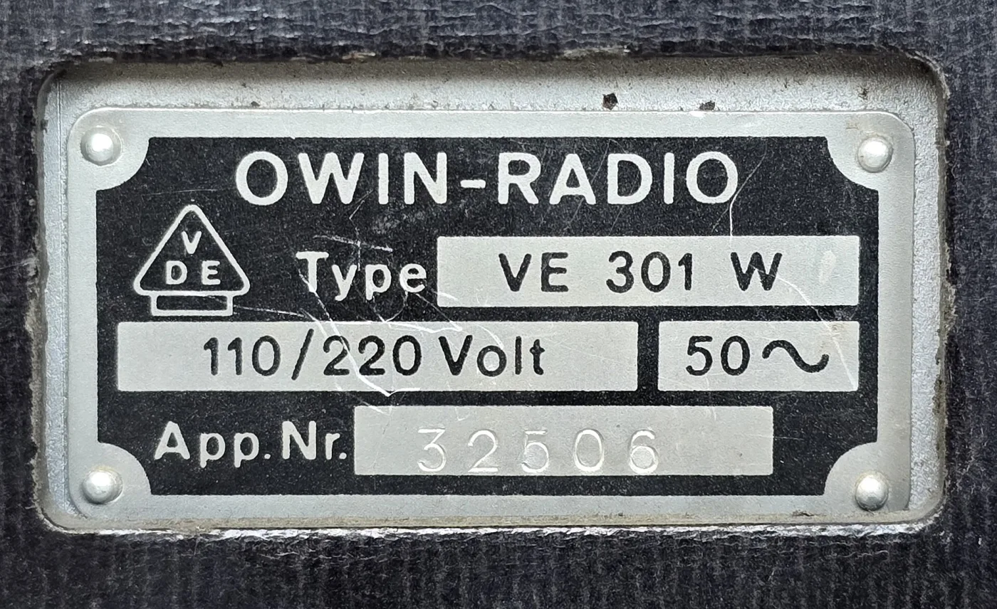 Metal data plate riveted to a radio cabinet, stamped OWIN-RADIO, Type VE 301 W, 110/220 Volt, 50 cycles, and an apparatus number