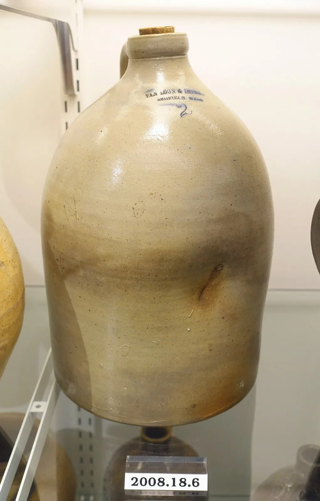Two-gallon grey salt-glazed stoneware jug with a rounded ovoid shoulder tapering to a short collared neck holding a cork, a single strap handle, and an impressed maker's mark with cobalt rubbed into the letters above a hand-drawn cobalt numeral 2