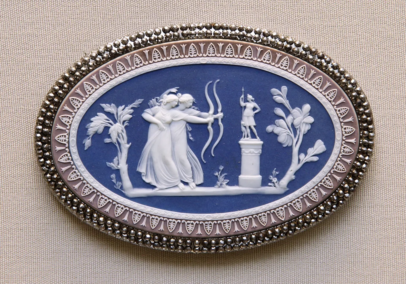 Oval Wedgwood jasper plaque with white classical figures on a blue ground and a lilac border, set in a faceted cut-steel mount